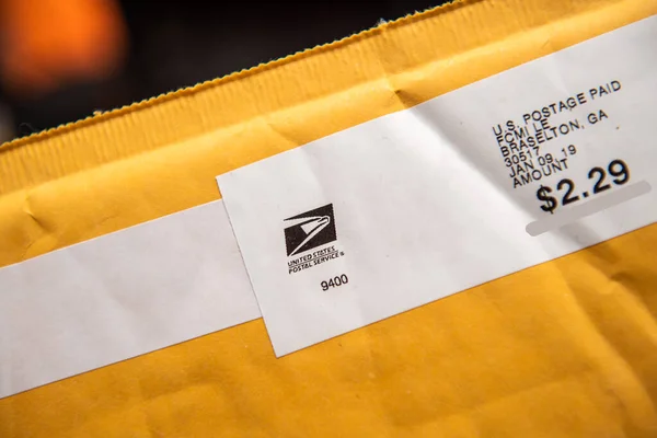 Close-up macro shot of yellow envelope with logotype insignia of United States POstal Service eagle and price of 2.29 usd — Stock Photo, Image