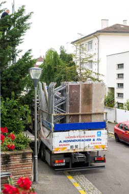 Dış cephenin yenilenmesi nedeniyle evin önüne park edilmiş büyük bir kamyonun iskelesi, sokak manzarası.