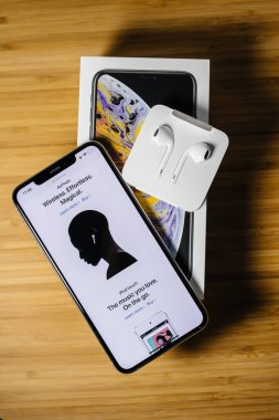 En son Apple Bilgisayarlarının paketini açmak, AirPods ve yepyeni Apple Bilgisayarları 'nın web sayfasının yer aldığı akıllı telefonlu iPhone' u açmak, yıldırımlı kulaklıklar, ahşap arka plan.