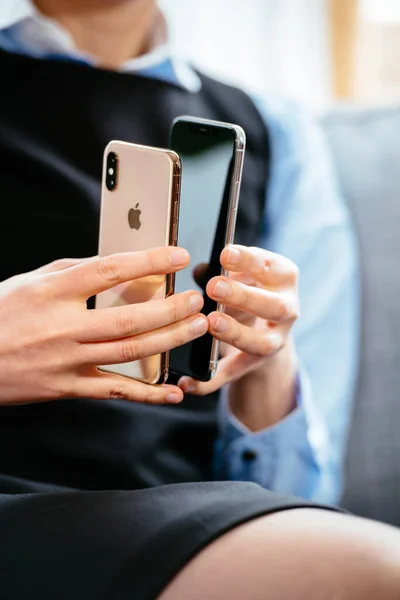 Frau vergleicht zwei neue Apple-Computer iPhone-Versionen normal und Max - Fokus auf Hände mit Handylogo — Stockfoto