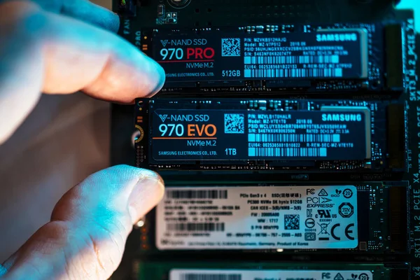 Close-up view of man hand inserting in the M2 connector the new Samsung NVME V-Nand SSD Samsung 970 disk drive next to Pro and other brand — Stock Photo, Image