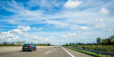 Güneşli bir günde otoban. Dağınık kümülüs bulutu cand VOLVO V70 vagon karavanın yanında.