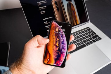 POV erkek eli en son Apple Bilgisayarları iPhone Max akıllı telefonu arka planda MacBook Pro çalışan büyük retina görüntüsü OLED