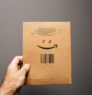 POV erkek eli Amazon Prime amblem zarfını tutuyor ve gülümseyen bir insan karakteri oluşturmak için kırmızı gözler ekliyor.
