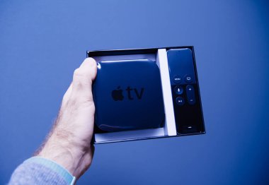Erkek el ele tutuşması, kutulanmamış Apple TV 'yi gösteriyor. Dijital medya oynatıcısı ve mikro konsol Apple Bilgisayar Şirketi tarafından geliştirildi ve satıldı.