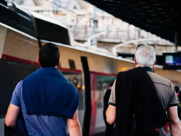 Vista trasera de dos hombres uno con gris y otro con el pelo blanco caminando hacia vagón de tren en la estación de tren francesa —  Fotos de Stock