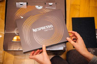 POV 'lu kadın elinde çeşitli renkli Nespresso Vertuo kahve kapsülleri paketini açıyor. Bir çeşit önceden bölünmüş tek kullanımlık kahve kabı.