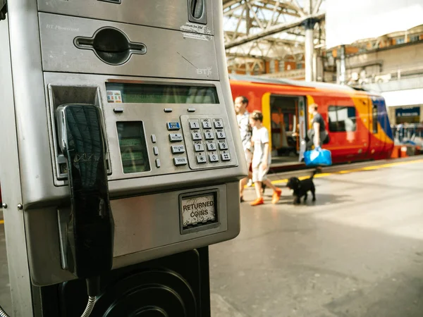 BT British Telecom Vintage telefono pubblico in stazione ferroviaria britannica con famiglia con cane imbarco treno sullo sfondo — Foto Stock