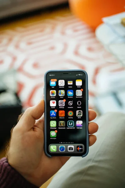 POV männliche Hand hält neue Apple Computer iPhone Smartphone mit Home-Bildschirm mit mehreren Apps Anwendungen — Stockfoto