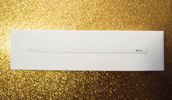 Vista aérea del logotipo de la insignia del lápiz de Apple en el paquete de cartón colocado sobre el fondo dorado brillo — Foto de Stock