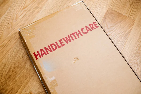 Handle with care inscription on the cardboard box of a new parcel delivered by freight — Stock Photo, Image