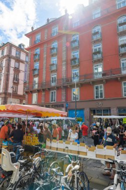 Grande Braderie Caddesi 'ndeki fuar fuarı sırasında müşteriler ve satıcılarla güneş ışığı parlıyor. Maskesiz müşterilerle dolu bir hayattan önce.