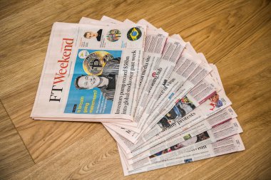 Mutfak tezgahında Elon Musk 'un gülümsemesi ve metni ile birlikte birden fazla Financial Times gazetesi yığını var.