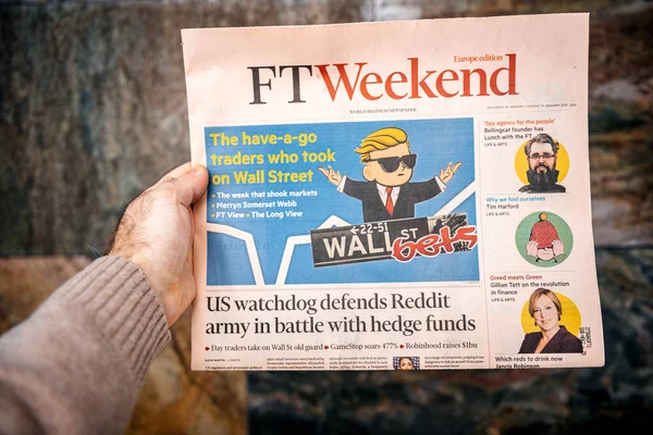 Мужчина, держащий за руку газету Financial Times FT, читающую о Уолл-стрит, делает ставки на форуме Reddit — стоковое фото
