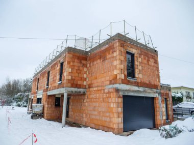 Alçak açı geniş açılı bitmemiş tuğla ev modern mülk kış günü karla kaplı bahçe.