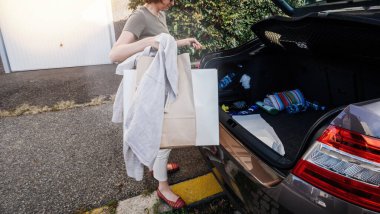 Alışveriş yaptıktan sonra bagajı çoklu torbayla boşaltan genç bir kadın.