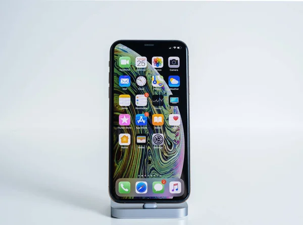 Isolert på den siste hvite Apple Computers Iphone Smartphone XS MAx telefonen med alle hjemme skjermapper som lades på dokkingstasjonen – stockfoto