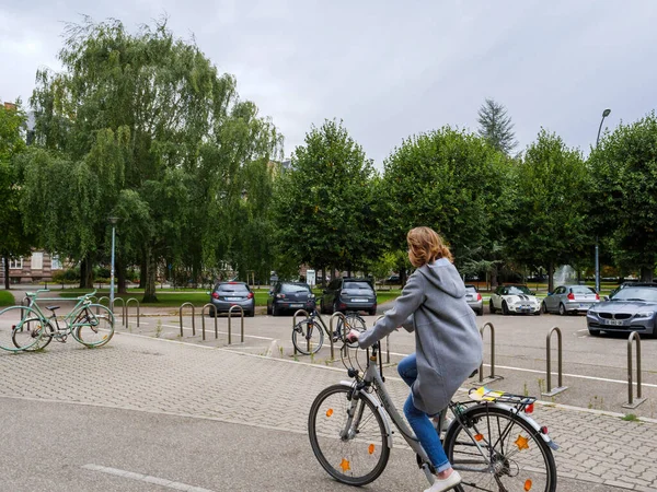 Πλευρική άποψη της νεαρής γυναίκας που οδηγεί ποδήλατο στο κέντρο του Στρασβούργου στην Place de lUniversite — Φωτογραφία Αρχείου