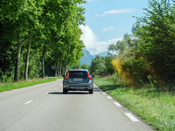 Vista traseira do carro sueco cinzento Volvo V 60 que conduz na estrada rural francesa com montanhas altas — Fotografia de Stock