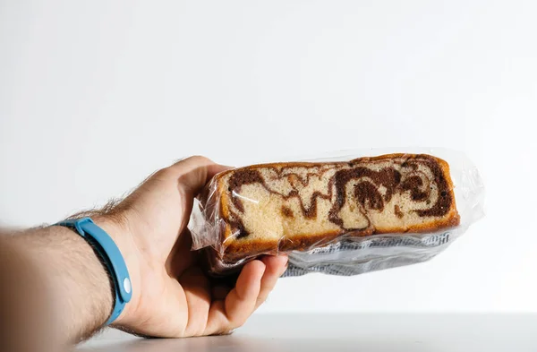 Holding an unopened package of chocolate cake — Stock Photo, Image