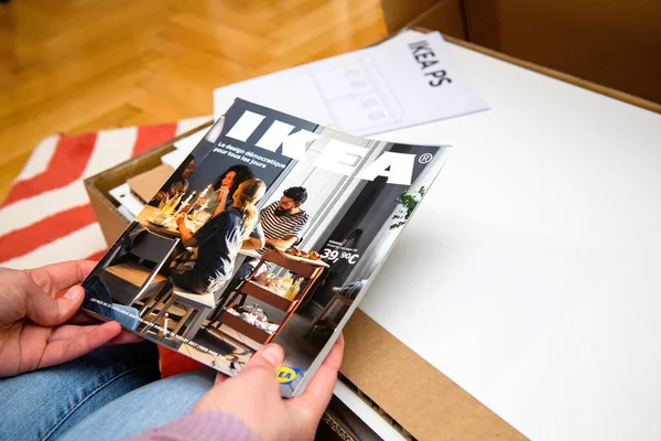 Mulher lendo catálogo IKEA acima da caixa de papelão — Fotografia de Stock