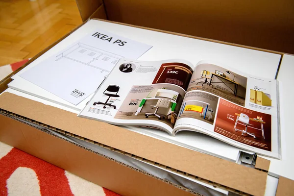 Páginas abiertas que leen el catálogo de IKEA encima de la caja de cartón — Foto de Stock