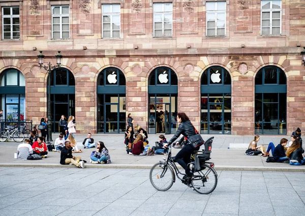 Apple Store 'un önünde bir grup insan yemek yiyor, içiyor ve eğleniyor.