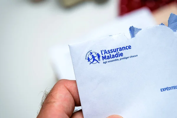 Рука держит открытый конверт от страховой болезни переводится как французская медицинская страховка — стоковое фото