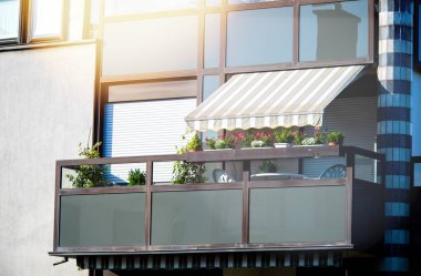 Sushade korumalı güneşliği olan güzel bir apartman balkonu.