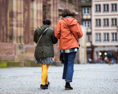 Tanımlanamayan kadın arkadaşlarının arka görüntüsü kaldırım taşlı yolda yürüyen çift