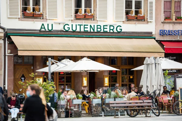 Folk äter på Au Gutenbergs terrass som barer och restauranger — Stockfoto