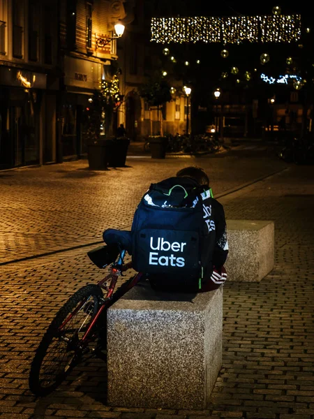 Lonely uber eats app driver delivery young man sitting on the stone urban furniture — Stock Photo, Image