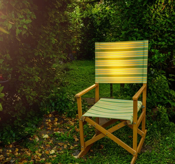 Chaise de jardin éclairée par le soleil au coucher du soleil dans le jardin verdoyant rustique — Photo