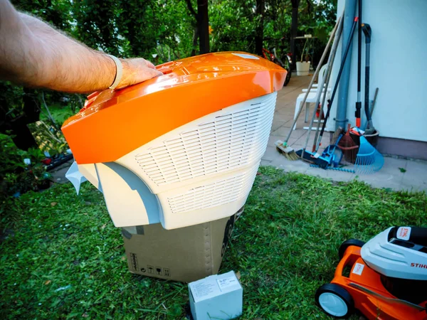 POV erkek eli yeni turuncu çim biçme makinesi 55 Litre tutuyor. — Stok fotoğraf