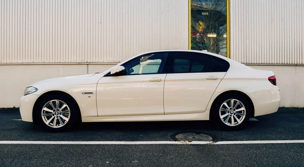 Nuevo coche blanco BMW limusina estacionado contra la pared de rayas blancas — Foto de Stock