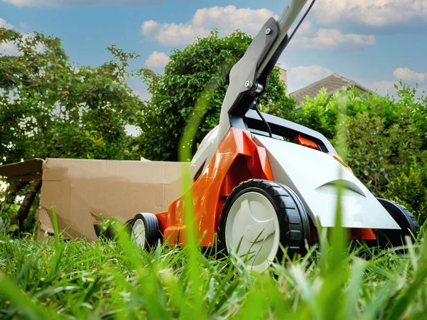 Nuovo tosaerba non in scatola in giardino con alberi alti sullo sfondo — Foto Stock