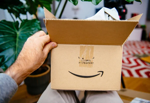 POV mano masculina sosteniendo unboxing la nueva parcela de Amazon.jp Japón y texto jeroglífico — Foto de Stock