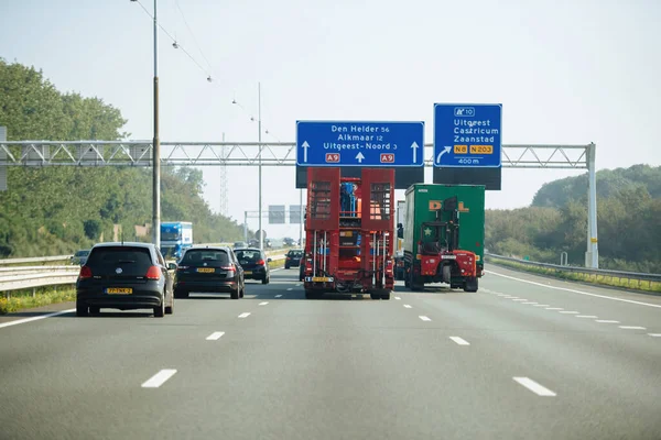 Drukke Nederlandse snelweg met vrachtwagens onder de snelweg bewegwijzering met pijlen — Stockfoto