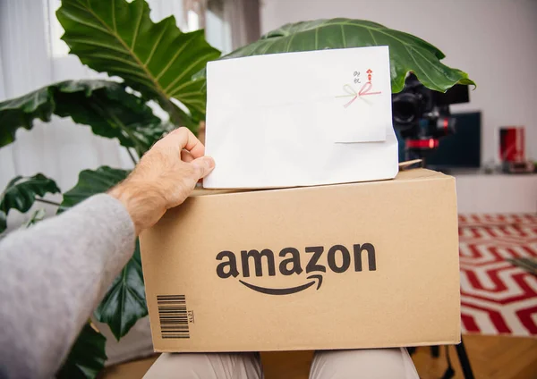 POV mužská ruka drží rozbalování nového balíčku z Amazon.jp Japonsko a hieroglyfický text — Stock fotografie