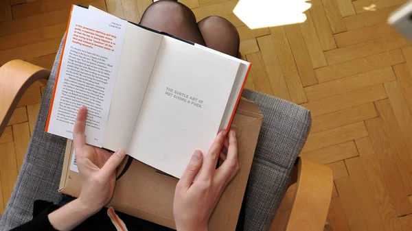 Woman reading new delivered book from Amazon with title The subtle art of not giving a fuck — Stok fotoğraf