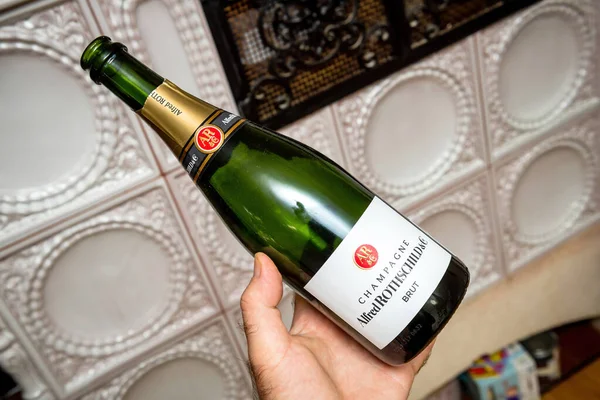 Homem segurando nova garrafa vazia de Alfred Rothschild and Company garrafa de champanhe com forno de luxo no fundo — Fotografia de Stock