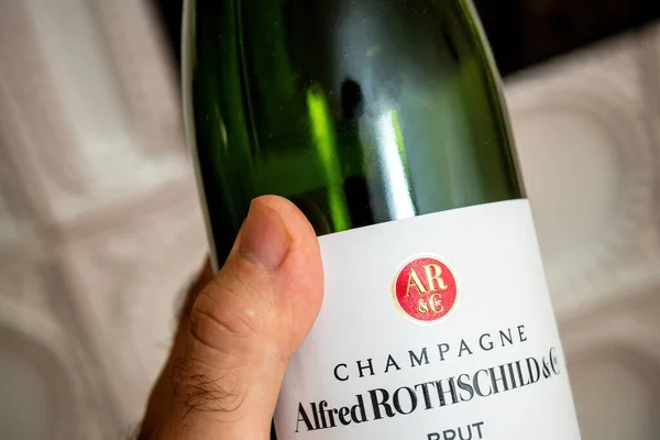 Man håller ny tom flaska Alfred Rothschild and Company champagne flaska med lyx ugn i bakgrunden — Stockfoto