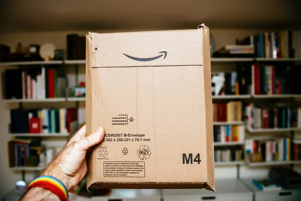 POV mannelijke hand houden van nieuwe pakket geleverd door Amazon Prime met achteraanzicht enveloppe codes — Stockfoto