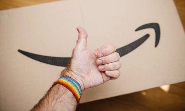 Arka planda Amazon kartonlarının olduğu eşcinsel bir bilezik takıyor.