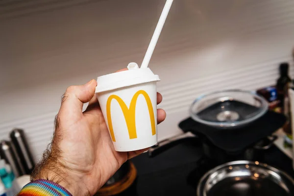 POV mano masculina sosteniendo la taza de plástico con el logotipo de McDonalds en él y beber paja —  Fotos de Stock