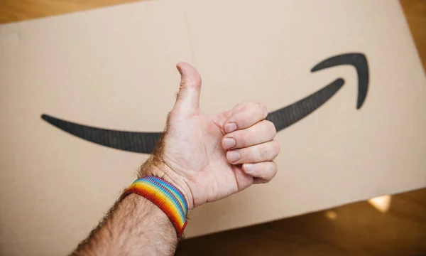 Aprobación de la mano signo de usar una pulsera gay con Amazon prime cardboard en el fondo — Foto de Stock