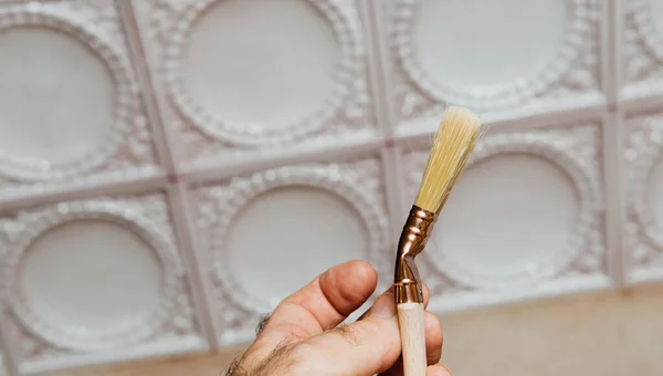 Mano masculina sosteniendo un nuevo pincel natural para la decoración del hogar — Foto de Stock