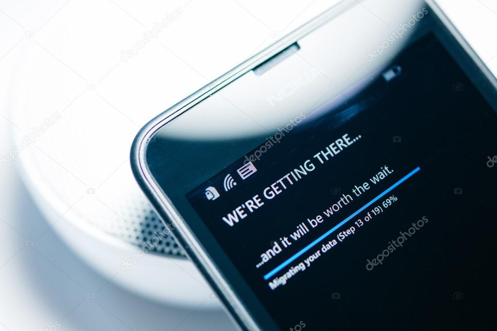 LONDON, UNITED KINGDOM - NOVEMBER 9, 2014: Nokia Lumia smartphone windowsphone with We're Getting There migrating data status bar percentage. Microsoft has announced that it will stop using Nokia branding on all future mobile phone