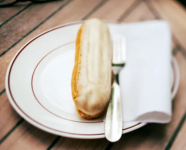 Eclair on plate at french cafe — Stock Photo, Image