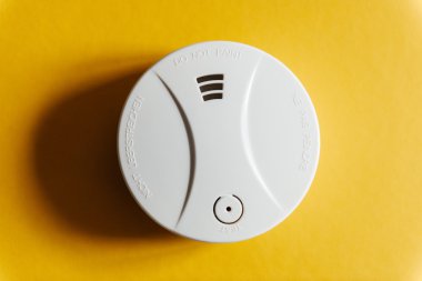 White smoke detector on yellow ceiling clipart
